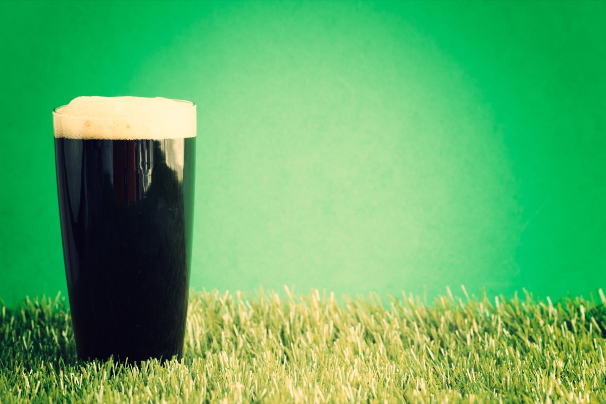 irish stout beer in a glass over grass and green background