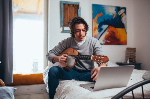 Bărbat făcând o lecție de chitară online