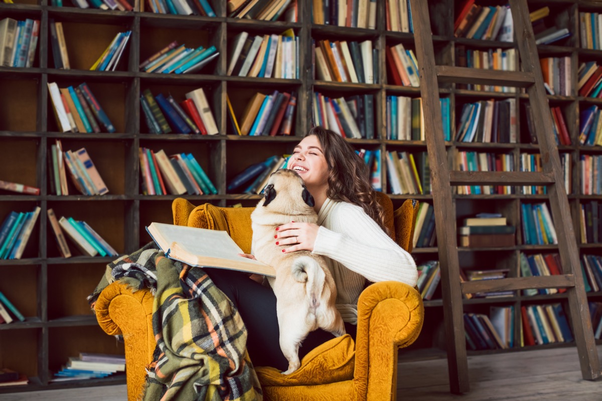 Girl reading in home library with dog