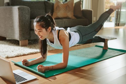 Девојка ради вежбе код куће са лаптопом