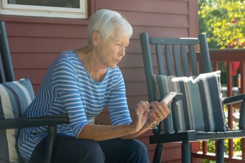 O bătrână albă trimite mesaje afară în timp ce pare îngrijorată