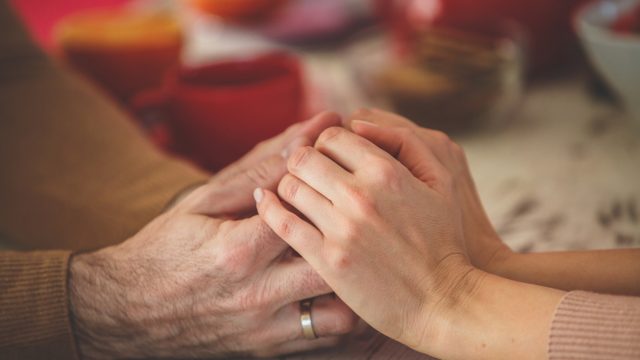 Close-up shot of a married couple holding hands across table, wife not wearing wedding ring