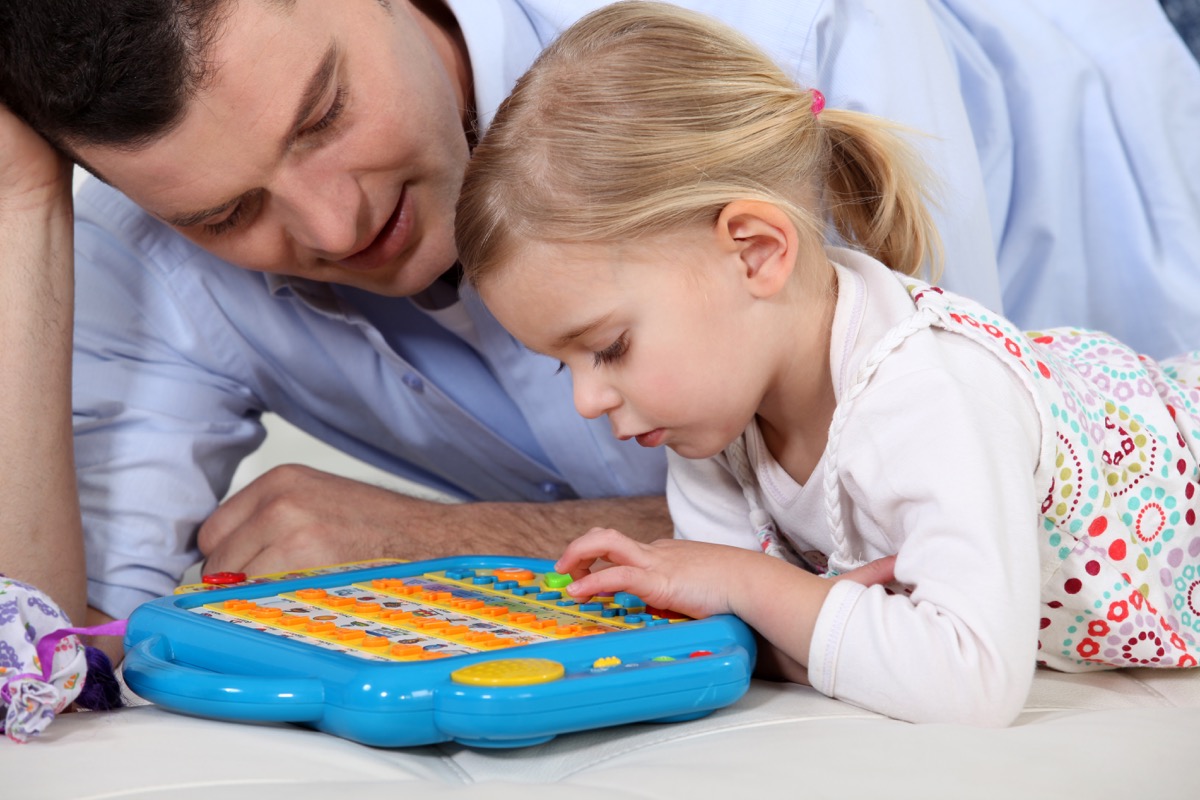young white girl playing with electronic toy with father