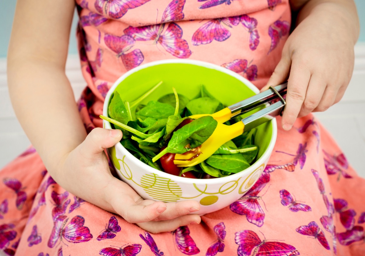 little girl eating spinach salad