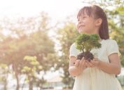 little girl holding plant oudoors