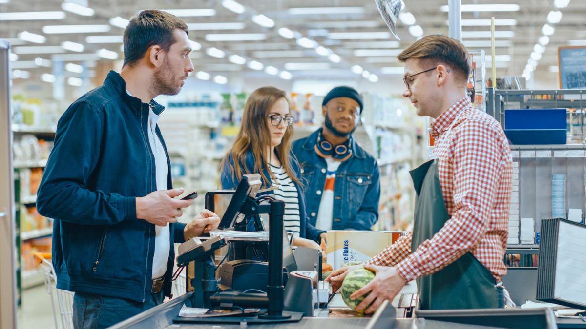 man arguing with cashier at store while other shoppers look on
