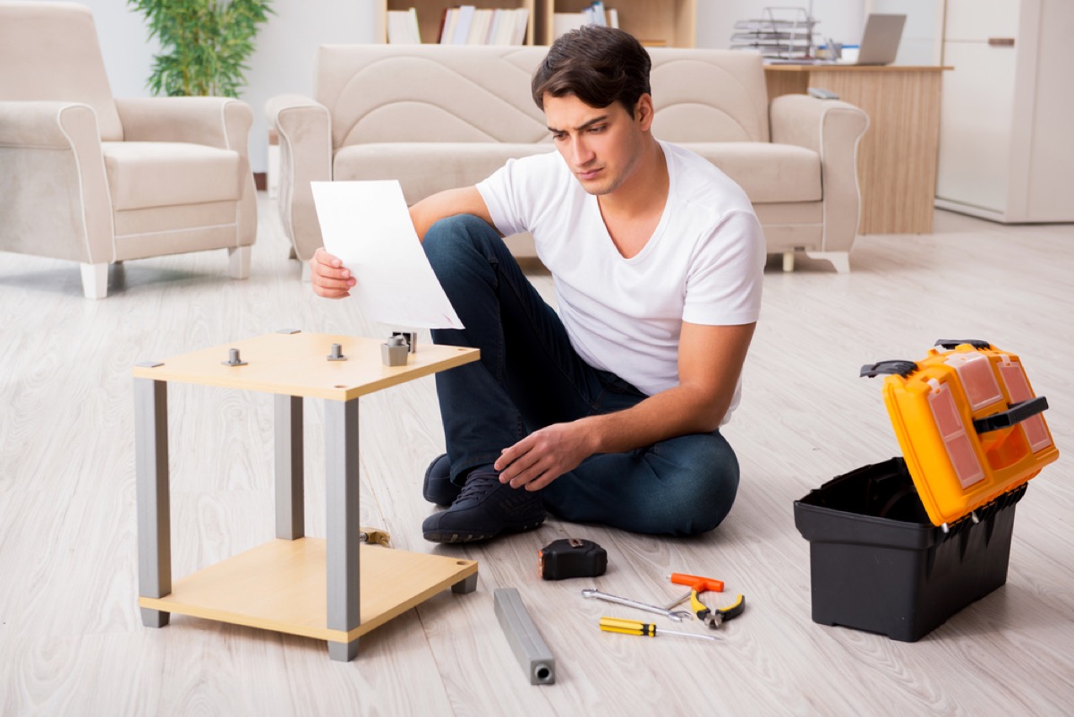 man struggling to assemble furniture on floor