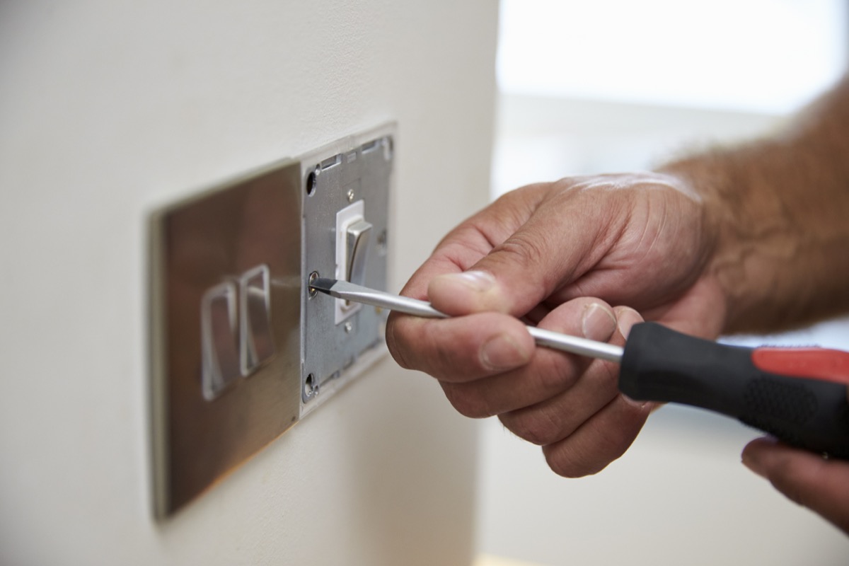 white hand installing light switch cover