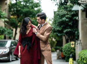 man helping woman put on her coat in the middle of the road