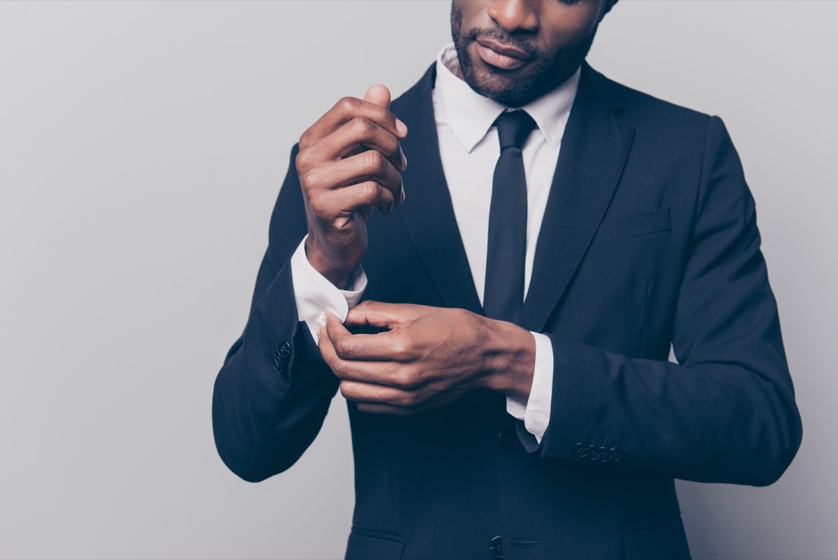 a man buttoning up his suit cuff before going into work