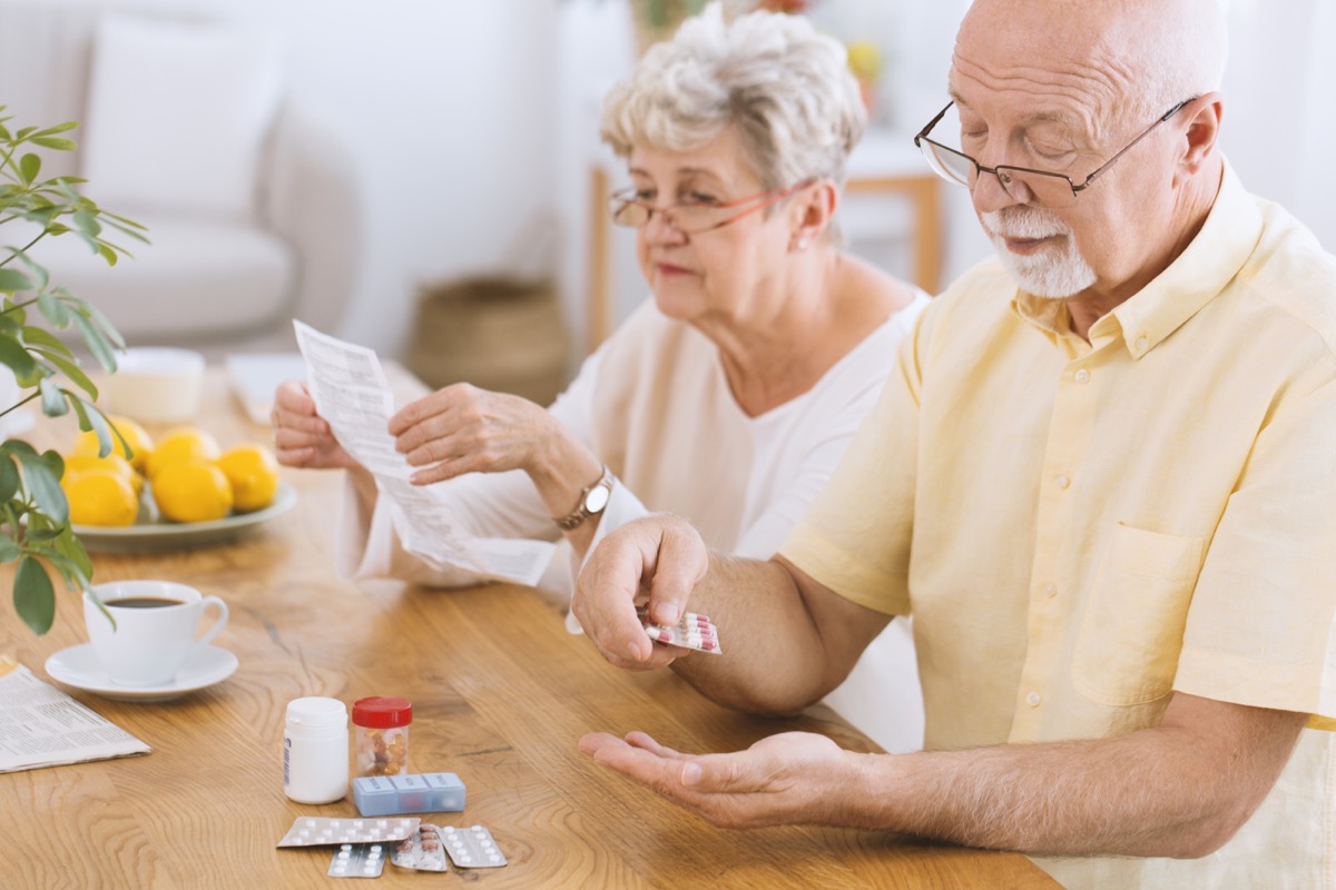 Older couple taking medications reading instructions carefully