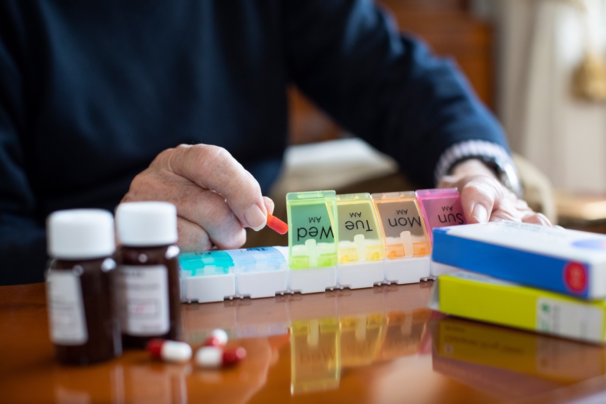 Older man sorting medication and vitamins in pill box