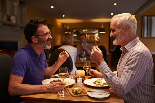 Middle aged male gay couple eating dinner in a restaurant