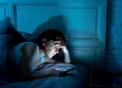 middle aged woman on her phone in bed at night