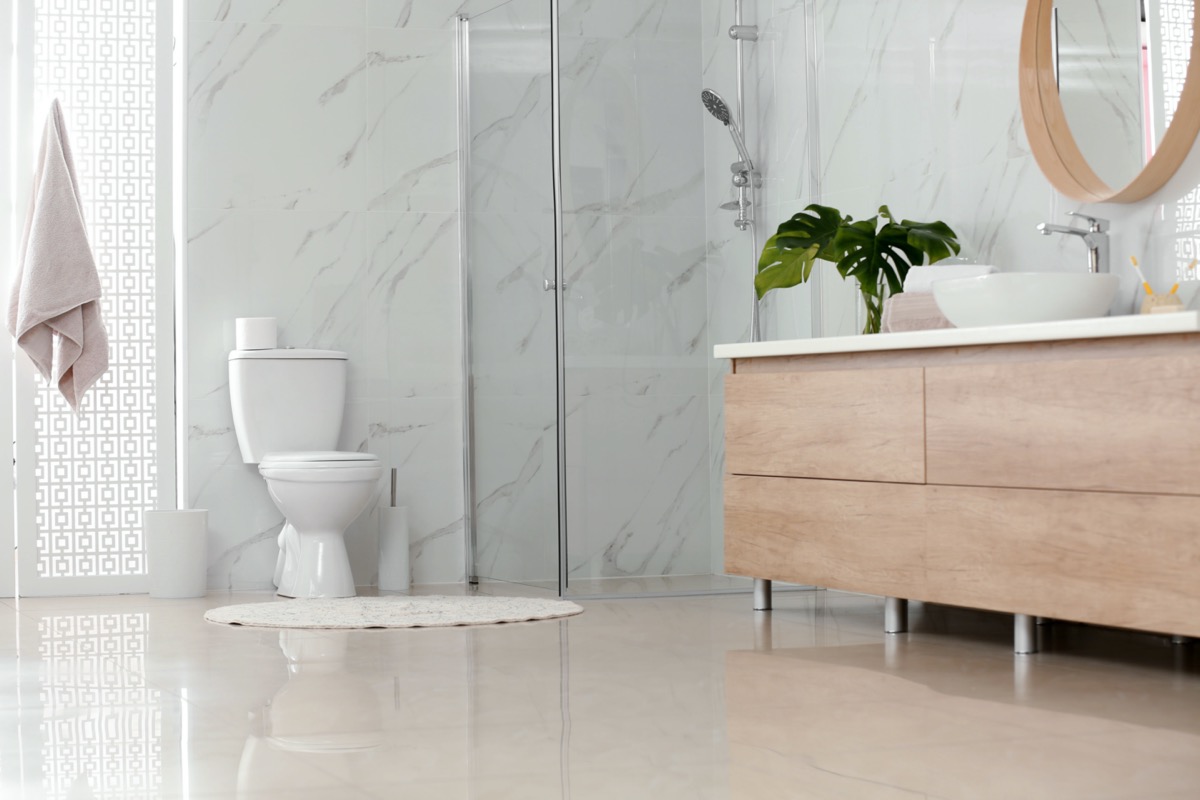modern bathroom with marble walls white toilet and light wood furniture