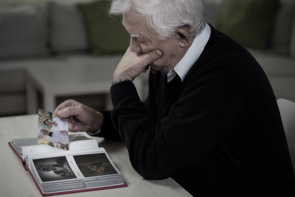 Old man looking at old pictures upset