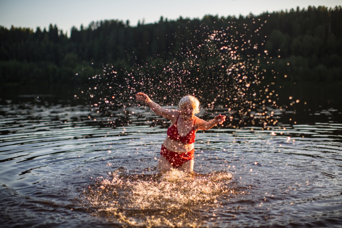 Older woman splashing and swimming in lake