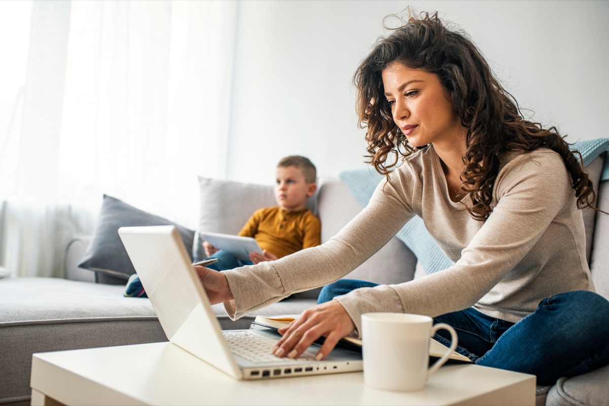 Parent on computer with child next to her