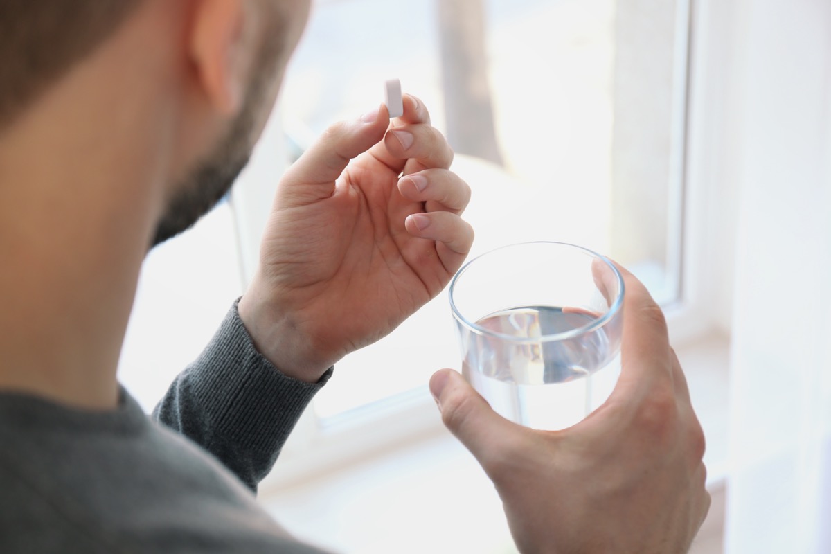Man taking a pill with a glass of water
