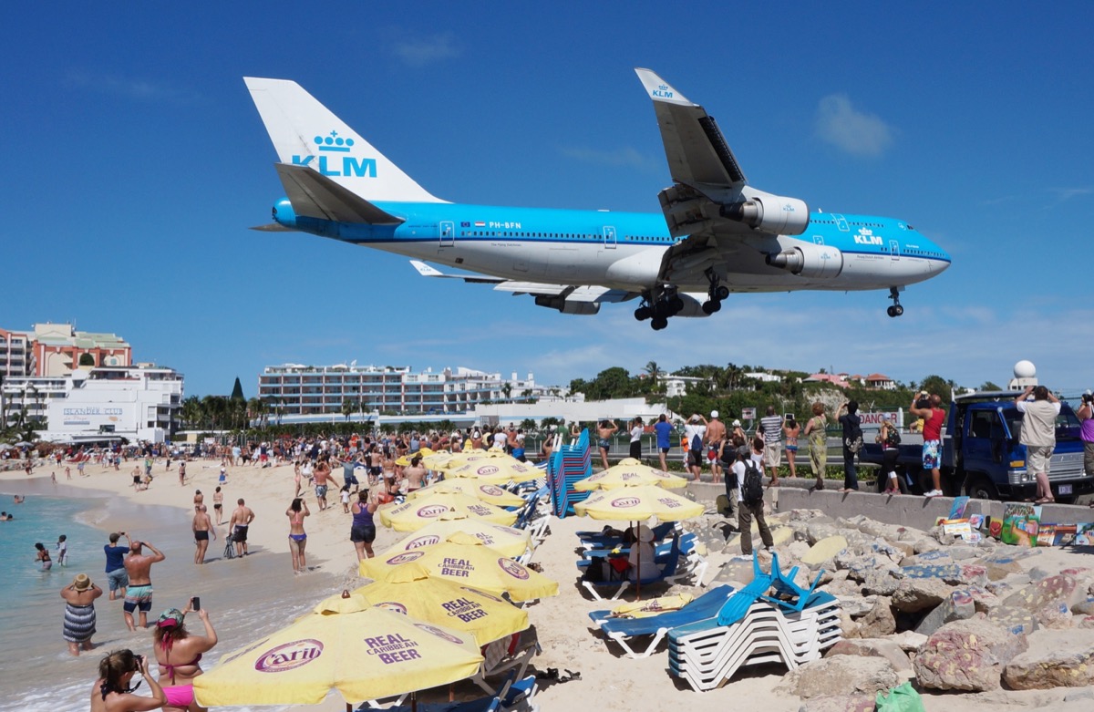 princess juliana airport with plane landing close to people at the beach