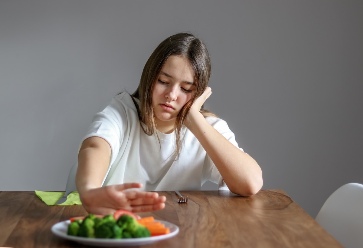 girl refusing a plate of vegetables