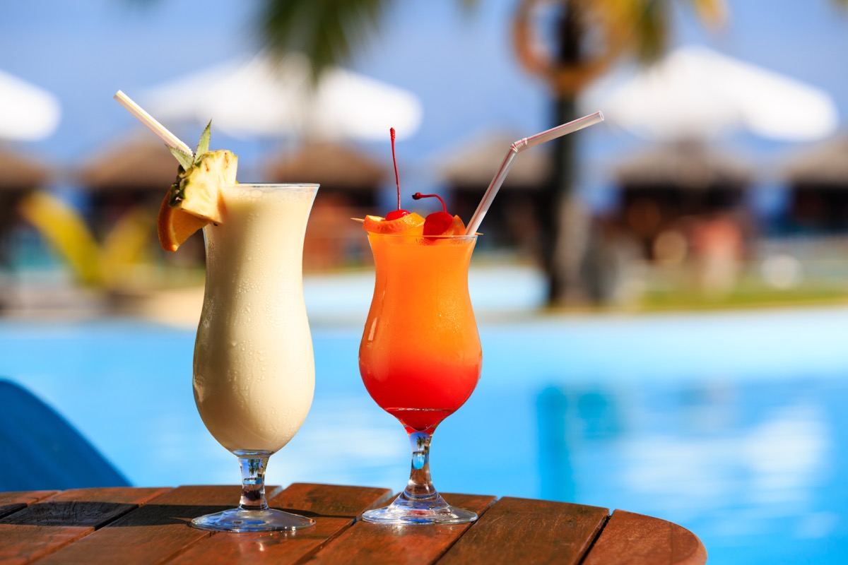 two glasses of cocktails near a resort pool