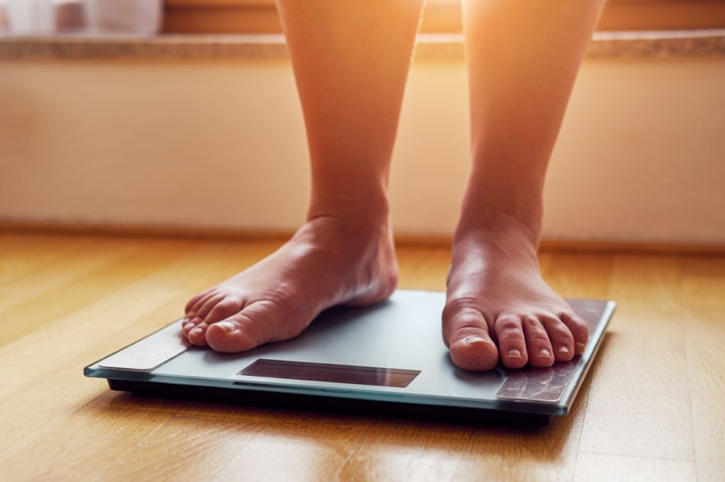 Woman stepping on a scale to weigh herself