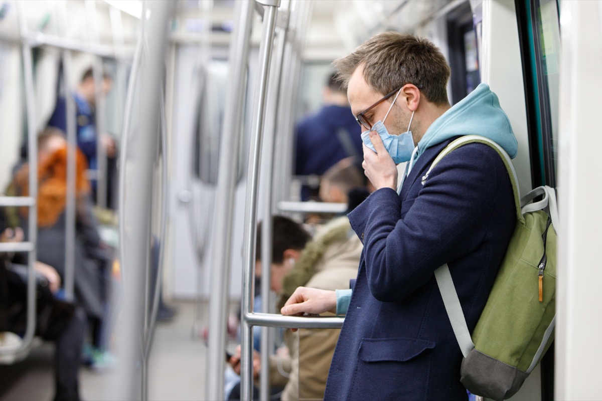 white man wearing mask and blue peacoat on subway during coronavirus covid-19 pandemic