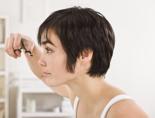 Close-up profile of a woman trimming her bangs. Horizontal shot.