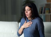 woman alone in house at night has hand on chest as she struggles to breath