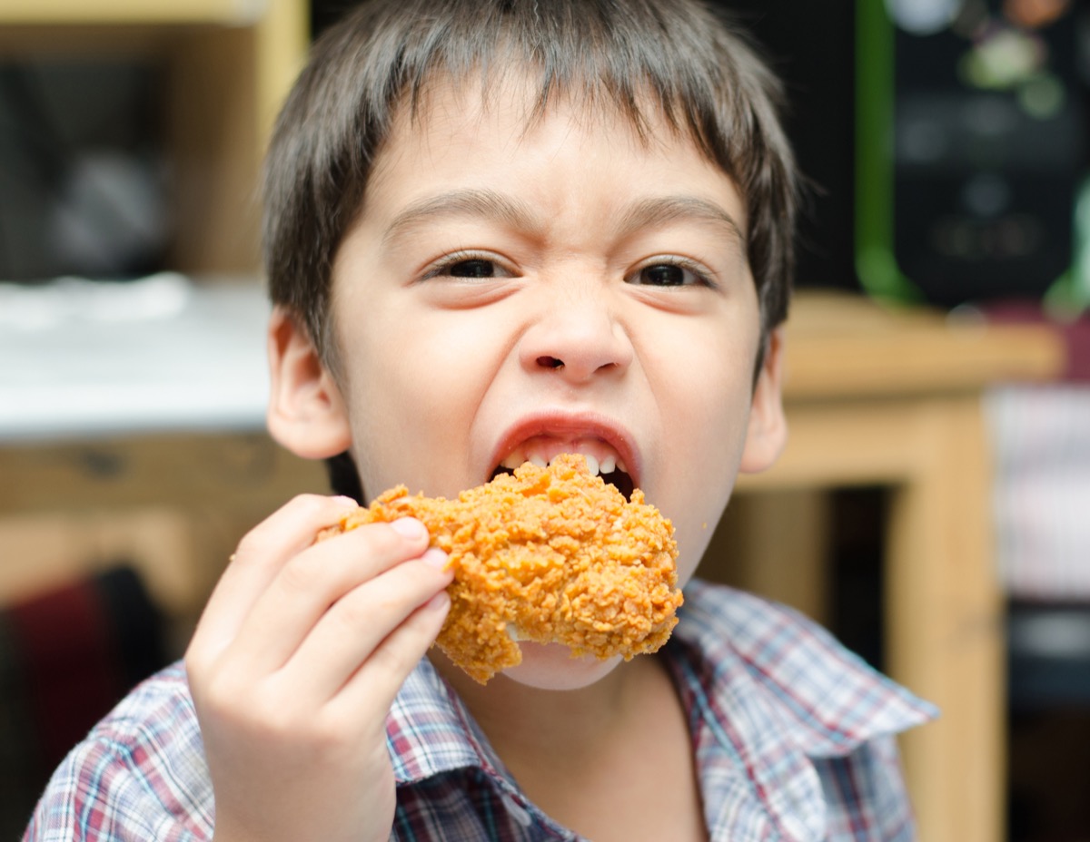 young asian boy eating fried chicken