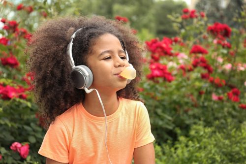 young girl in headphones blowing bubble with gum