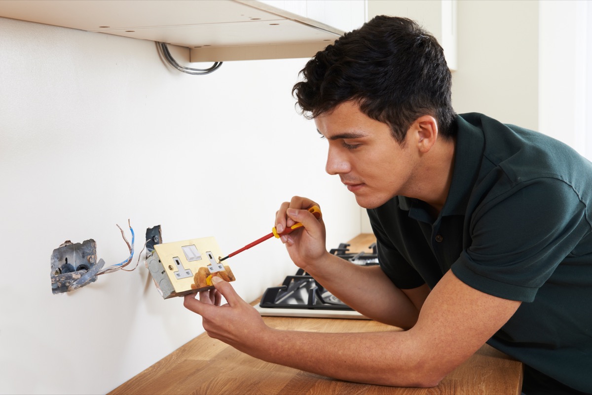 young electrician installing outlet