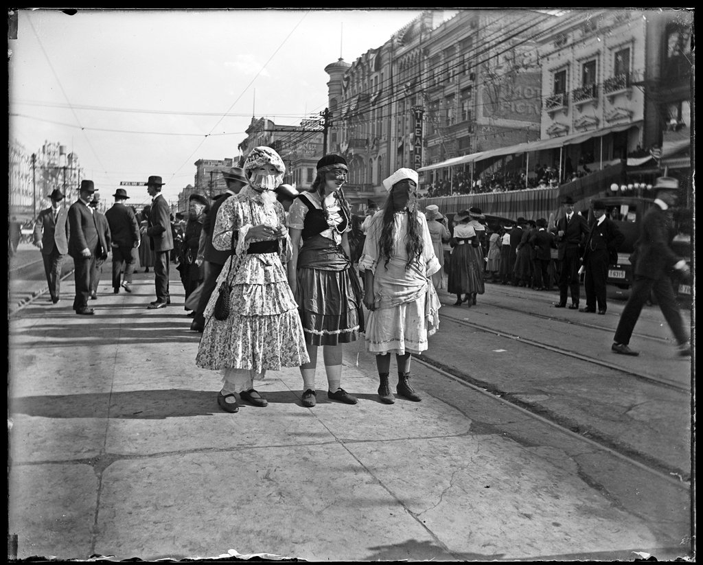crowds of people in costumes march through the streets of New Orleans for Mardi Gras in 1917
