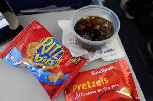 airplane snacks and soda on tray