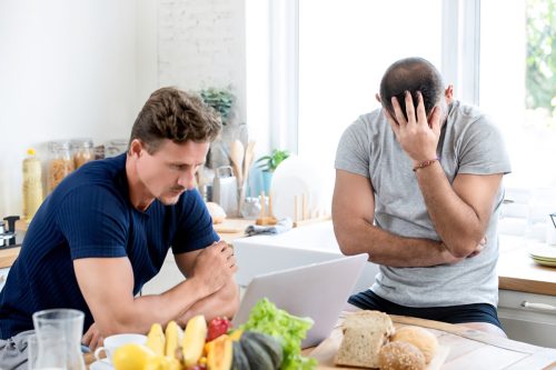 Men having a tense discussion in the kitchen