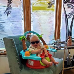 baby with sunglasses on in front of painted windows