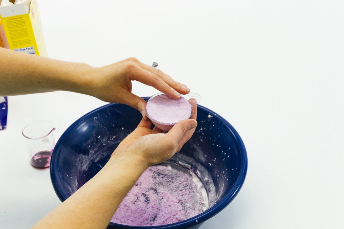 white hands making purple bath bomb