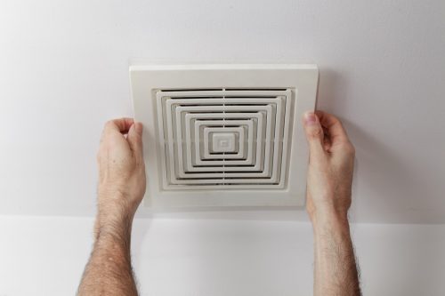 white hands holding bathroom exhaust fan