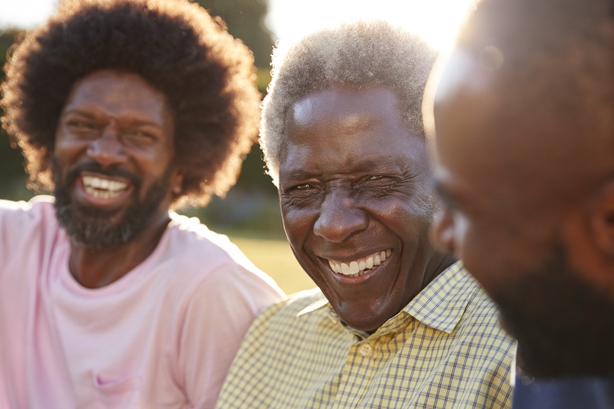 Senior black man laughing with his two adult sons