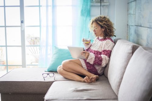 Woman on couch on laptop bright living room