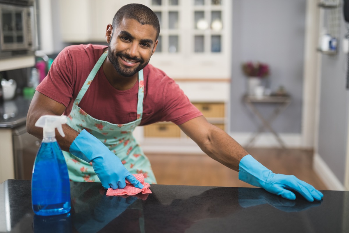 Man cleaning counter in kitchen