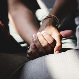 Closeup of couple holding hands on couch
