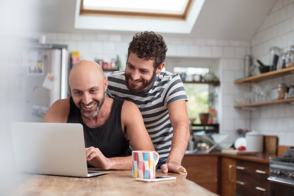 Couple looking at laptop in kitchen smiling