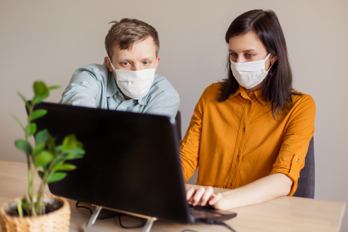 couple reading on computer while wearing masks