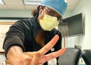 young black female doctor in protective gear giving a peace sign