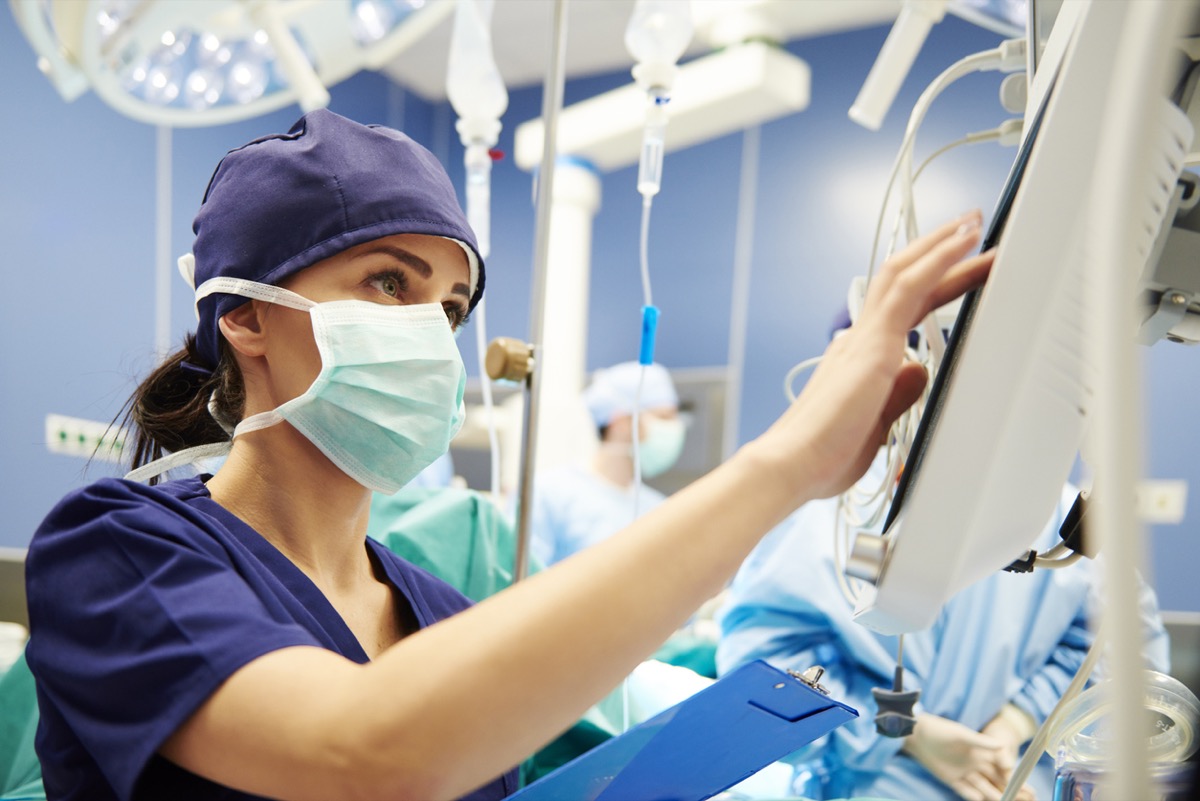 Young female medical professional working with technology in operating room