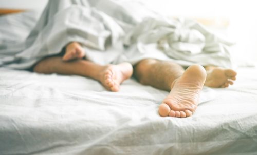 Prim-plan cu picioarele masculine și feminine pe pat
