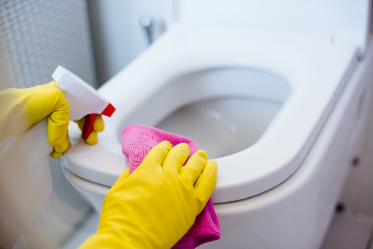 gloved hands cleaning toilet