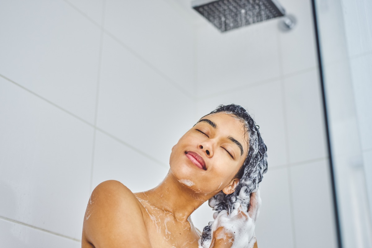 woman washing her hair in shower with shampoo